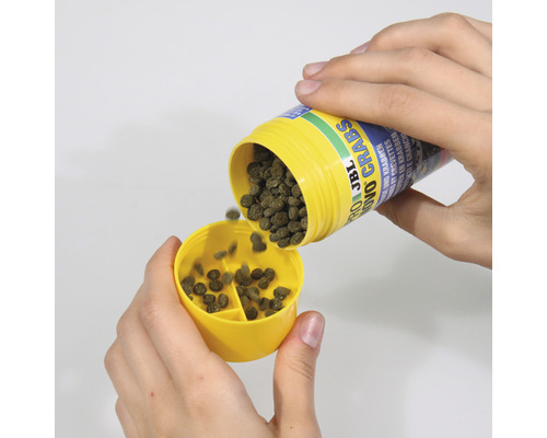 JBL Novo Crabs voer wordt in een geel doseerhulpstuk gegoten