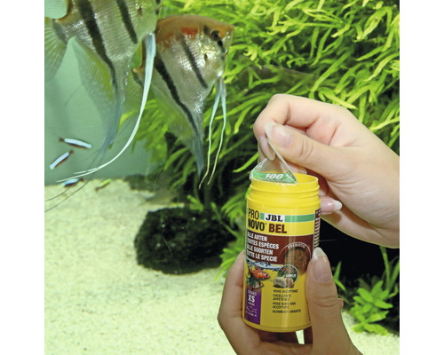 Persoon opent een pot JBL Pro Novo Bel visvoer voor een aquarium
