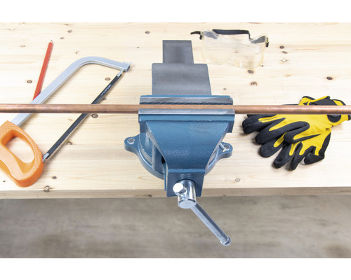 Werkbank met bankschroef, koperen buis, zaag, veiligheidsbril en handschoenen