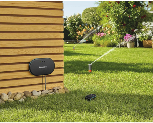 Gardena Smart System met controlecentrum, sensor en gazonsproeier in de tuin.