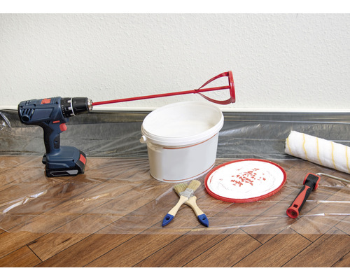 Scene met boormachine, verfmenger, verfemmer, kwasten en verfroller op een beschermfolie