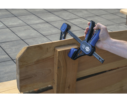 Hand houdt een eenhandsklem op hout