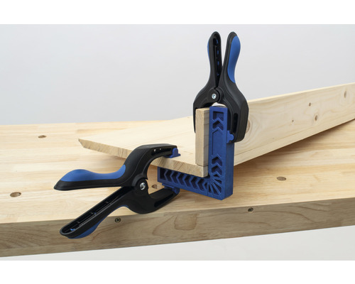 Twee stukken hout worden met een hoekklem en veren op een werkbank bevestigd.