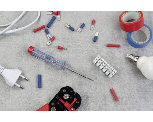 Diverse elektrische installatiematerialen, waaronder adereindhulzen, een kroonsteen, isolatietape, een gloeilamp, een spanningzoeker, een striptang en een stekker.