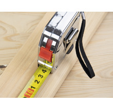 Een rolmaat ligt op een houten plank.
