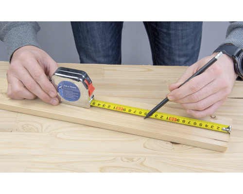Rolmaat en potlood voor het meten van een houten plank