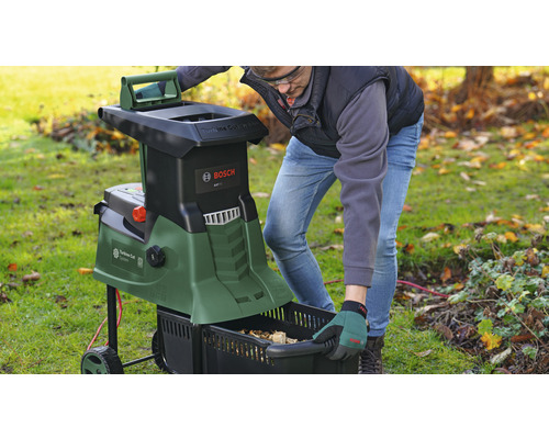 Tuinscène met een man die een hakselaar bedient en een opvangbak leegt. Bosch Logo.