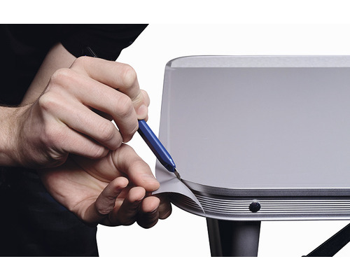 Iemand snijdt folie op een oppervlak met een mes.