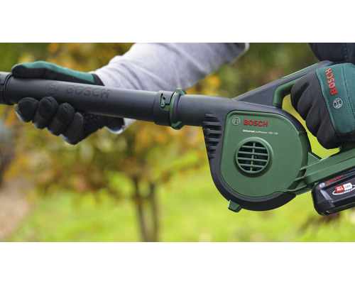 Een persoon houdt een accu bladblazer van het merk Bosch vast.