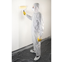 Persoon in beschermende kleding schildert een muur met een verfroller.