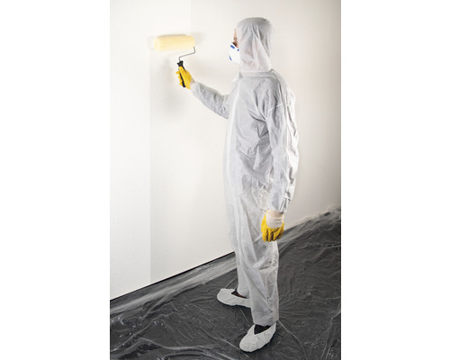 Persoon in beschermende kleding schildert een muur met een verfroller.