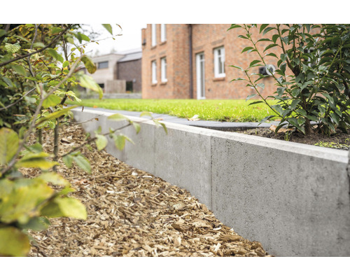 Tuinscene met gazon, huis en een betonnen gazonrand