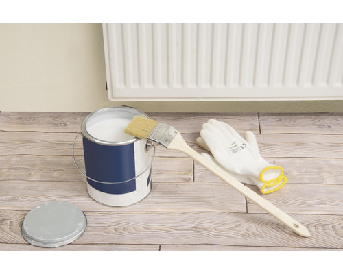 Verfemmer met verf, penseel en veiligheidshandschoenen op houten vloer