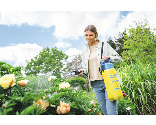 Vrouw gebruikt Gloria drukspuit in de tuin voor plantenverzorging