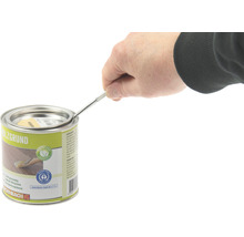 Een persoon opent een blik houtprimer met een gereedschap