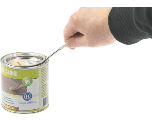 Een persoon opent een blik houtprimer met een gereedschap