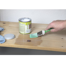 Houtbeits blik met penseel tijdens het aanbrengen op een houten plank