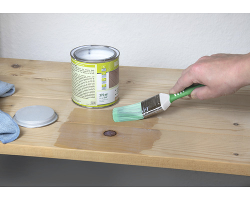 Houtbeits blik met penseel tijdens het aanbrengen op een houten plank