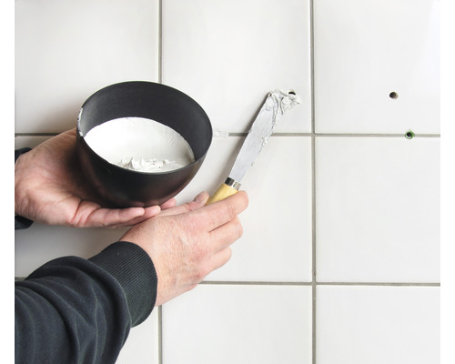 Tegelreparatie met plamuurmes en vulmateriaal