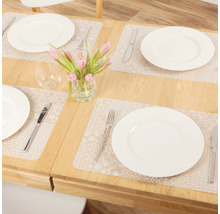 Gedekte eettafel met placemats, borden, bestek, glazen en bloemenvaas