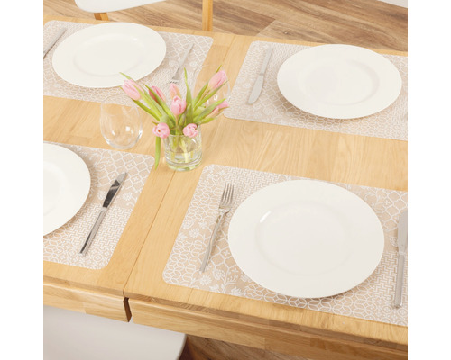 Gedekte eettafel met placemats, borden, bestek, glazen en bloemenvaas