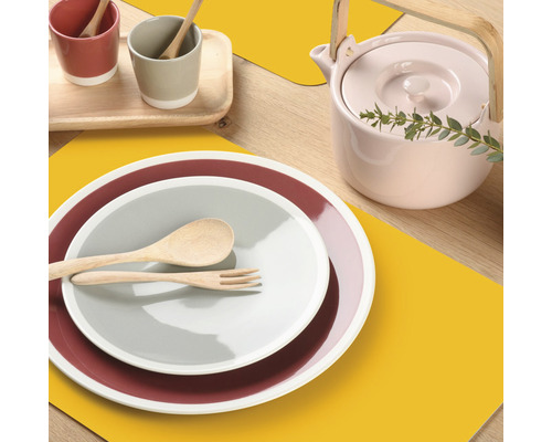 Tafeldecoratie met borden, bestek, bekers en theepot op placemats