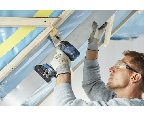 Een vakman bevestigt met een accuslagschroevendraaier een lat aan een houten constructie.