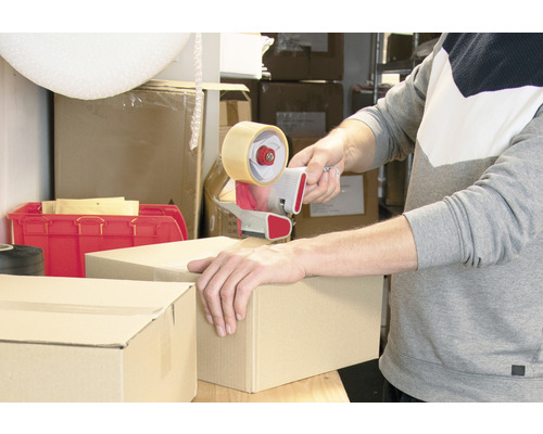 Iemand sluit een kartonnen doos met een tape dispenser.