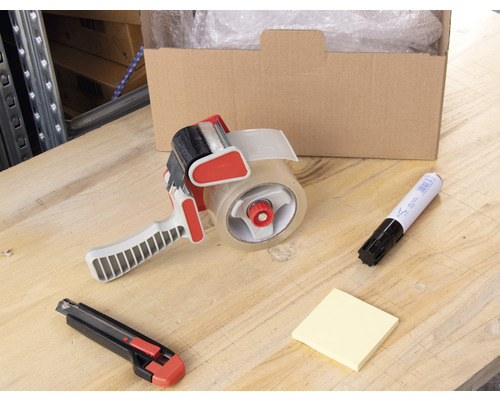 Karton, plakbanddispenser, markeerstift, notitieblaadjes en tapijtmes op een tafel.