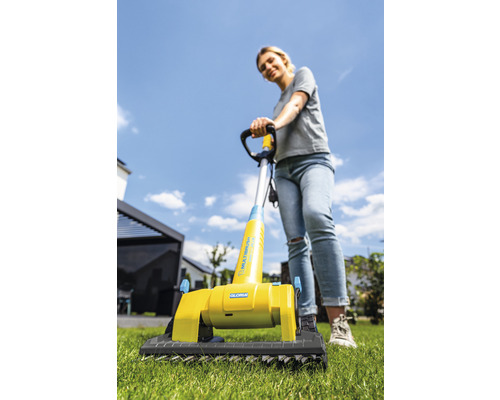 Vrouw gebruikt een Gloria multiborstel op gazon voor tuinonderhoud.