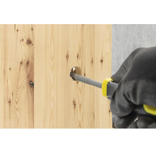 Een persoon vergroot met een houtrasp een gat in een houten plank.