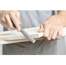 Een houtrasp wordt gebruikt om een stuk hout te bewerken.