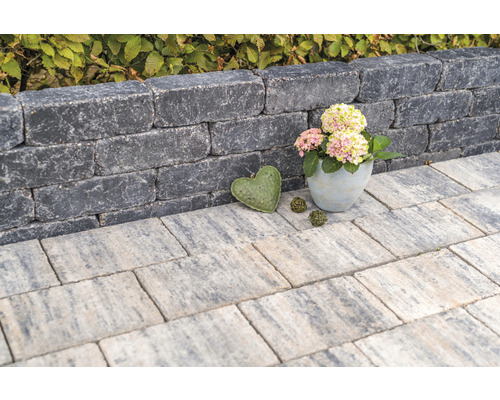 Gestapelde muurstenen vormen een kleine muur, aangevuld met stoeptegels en decoratieve elementen