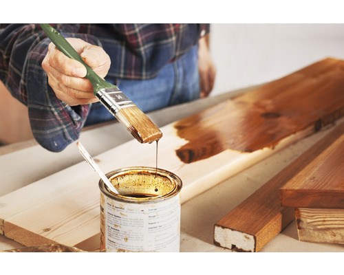 Houtbeschermingsbeits met een kwast aanbrengen op een houten plank