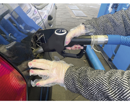 Een persoon met handschoenen tankt diesel in een auto.