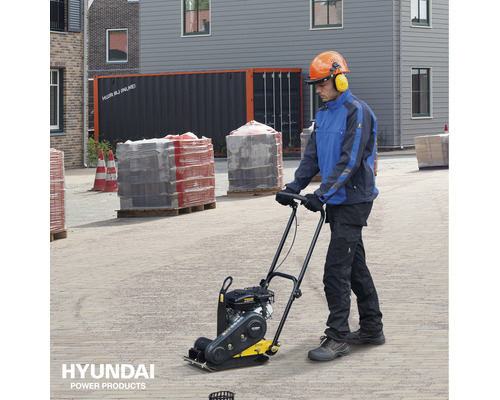 Een man bedient een trilplaat op een bouwplaats