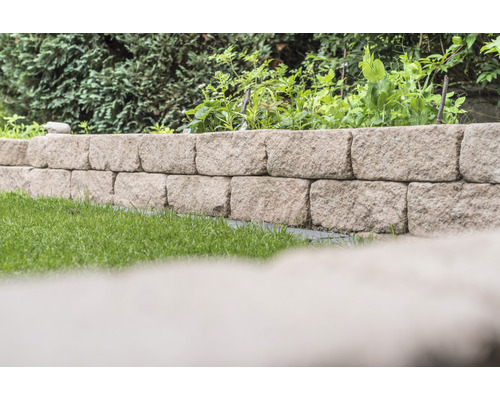 Tuin met een muur van natuursteen en begroeiing