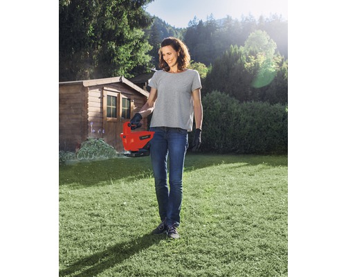 Vrouw gebruikt een elektrische grasschaar in de tuin.