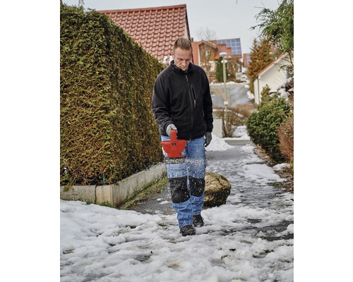 Man verwijdert sneeuw met een sneeuwfrees van een voetpad