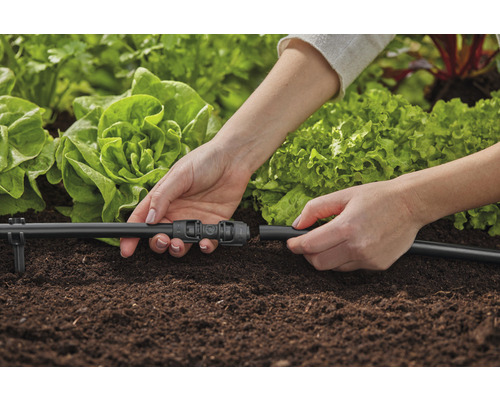Persoon verbindt irrigatiesysteem in de tuin
