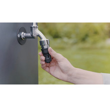 Een hand bevestigt een slangkoppeling aan een kraan voor tuinbesproeiing.
