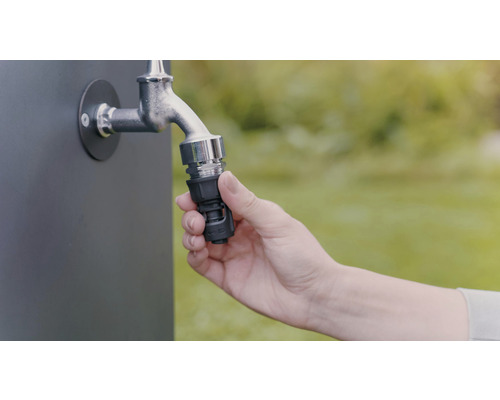 Een hand bevestigt een slangkoppeling aan een kraan voor tuinbesproeiing.