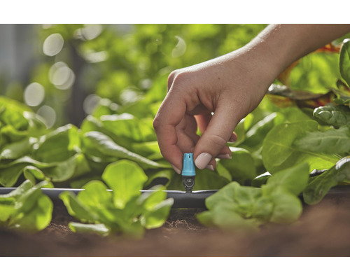Close-up van een hand die een irrigatiesysteem in de tuin aanpast