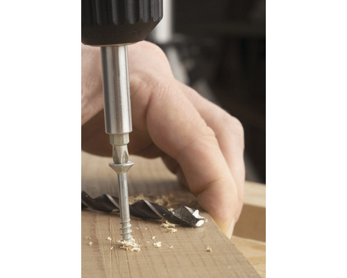 Een schroef wordt met een schroevendraaier in een stuk hout geschroefd.