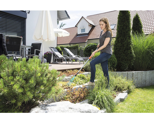 Vrouw werkt met een hark in de tuin.