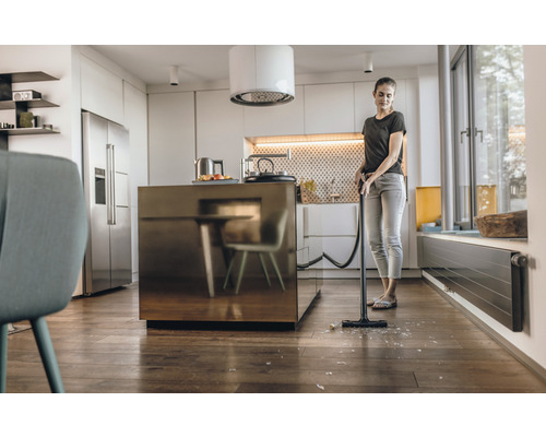 Vrouw zuigt glasscherven op met stofzuiger in de keuken