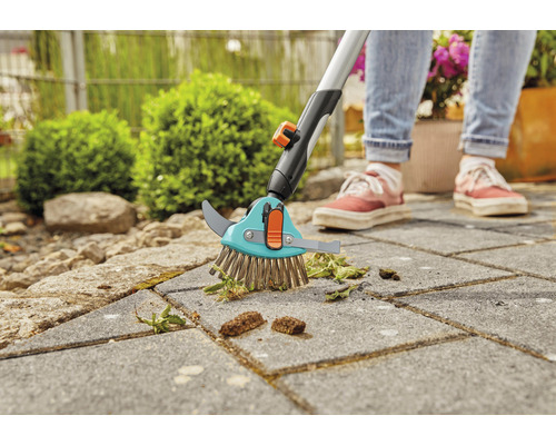 Voegenborstel met telescopische steel in gebruik op straatstenen voor onkruidverwijdering