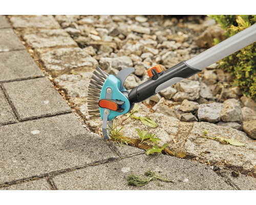 Voegenborstel in gebruik voor het verwijderen van onkruid tussen straatstenen