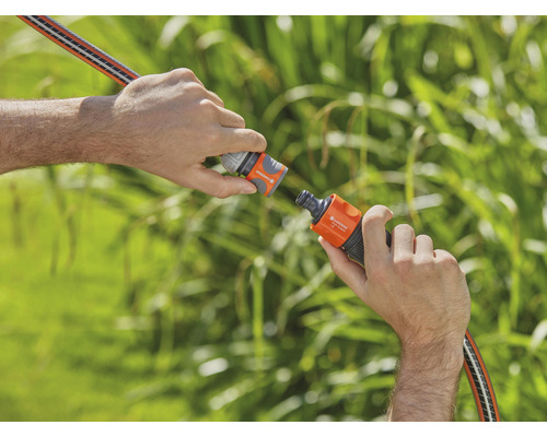 Twee handen verbinden een tuinslang met een slangverbinder.