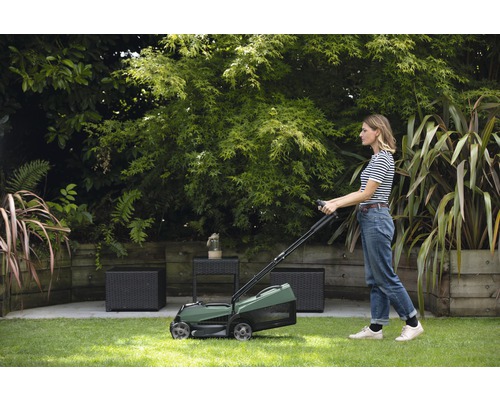 Een vrouw gebruikt een gazonbeluchter in de tuin.